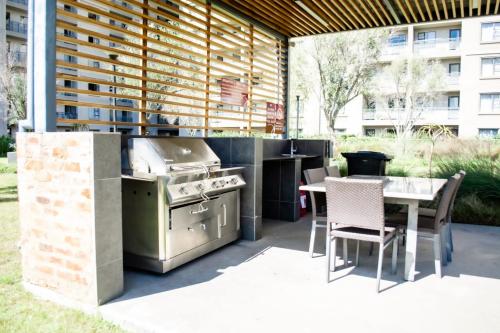 eine Terrasse mit einem Grill, einem Tisch und Stühlen in der Unterkunft The Westpoint Penthouse in Johannesburg