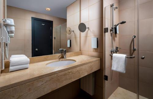 a bathroom with a sink and a shower at Leonardo Hotel Bucharest City Center in Bucharest