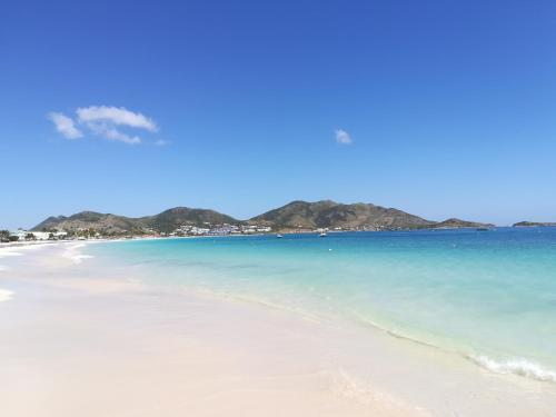 a beach with blue water and mountains in the background at Happy Residence - Orient Beach 09 in Cul de Sac
