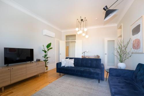 a living room with a blue couch and a tv at Entre Ruas Apartments in Coimbra
