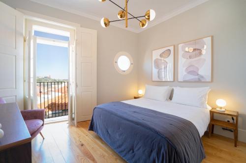 a bedroom with a large bed and a balcony at Entre Ruas Apartments in Coimbra