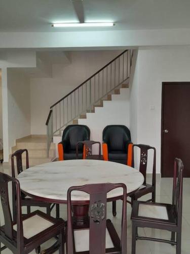 a table and chairs in a room with a staircase at Simple Home Taiping 简居 @ Suria Aman in Kamunting