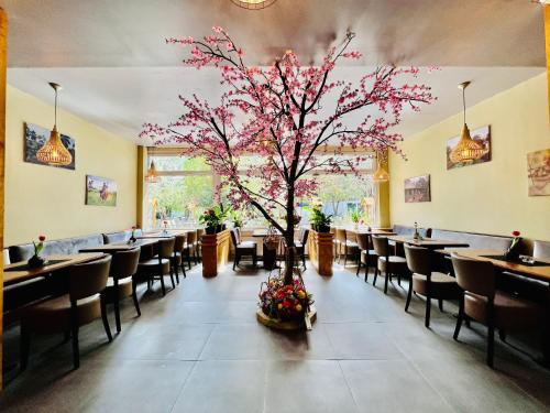 a restaurant with a tree in the middle of a dining room at Hotel My My in Lahnstein