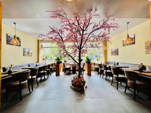um restaurante com uma árvore no meio de uma sala de jantar em Hotel My My em Lahnstein