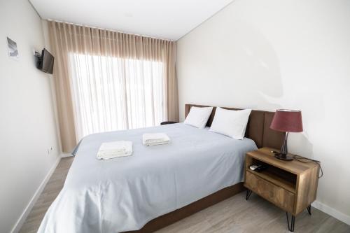 1 dormitorio con 1 cama blanca y 2 toallas en Meirinha House, en Viana do Castelo