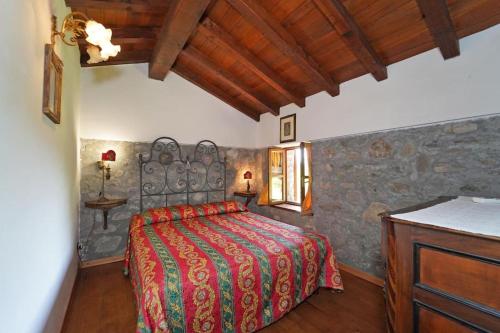 ein Schlafzimmer mit einem Bett und einer Steinmauer in der Unterkunft Villa Le Due Lune with Pool by VILLASRETREATS in Filattiera