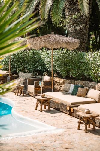 een patio met een bank en een parasol naast een zwembad bij Hotel Can Sastre in Santa Gertrudis de Fruitera