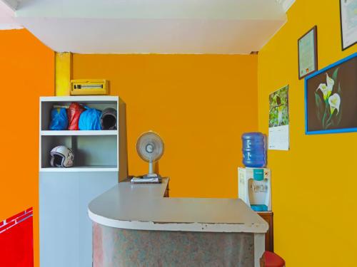 ノンガサにあるOYO 92496 Faraas Homestay Syariahのオレンジ色の壁の客室で、テーブルとファンが備わります。