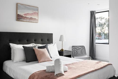 a bedroom with a large bed with white and pink pillows at Queensview168 Apartments Moonee Ponds in Melbourne