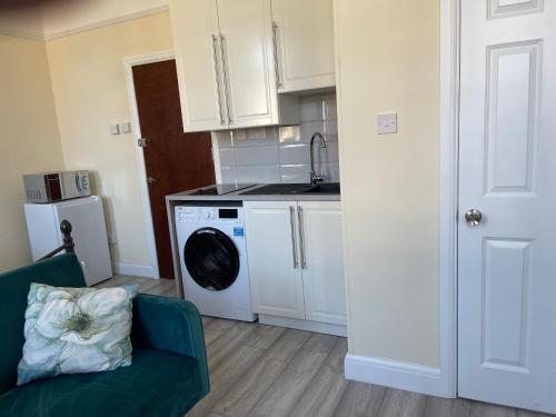 a kitchen with a washing machine and a green couch at Cosy Studio With Full Facilities. in London