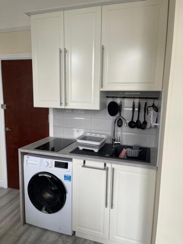 a kitchen with white cabinets and a washing machine at Cosy Studio With Full Facilities. in London