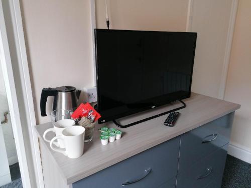 a tv sitting on top of a dresser with coffee cups at The Queens Head in Ashby de la Zouch