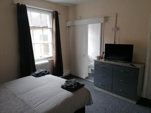 a bedroom with a bed and a television and a dresser at The Queens Head in Ashby de la Zouch