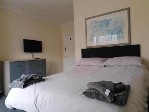 um quarto com uma cama branca, uma cómoda e uma televisão em The Queens Head em Ashby de la Zouch