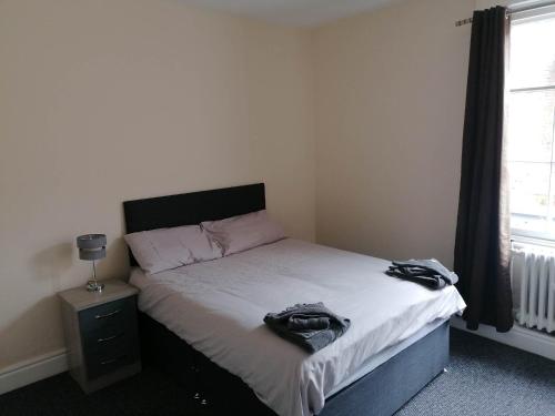 a bedroom with a bed with a black headboard and a window at The Queens Head in Ashby de la Zouch