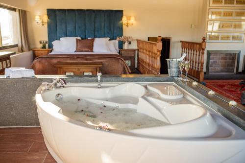 a bath tub in front of a bedroom with a bed at Hotel Roger de Flor by Seleqtta in Lloret de Mar