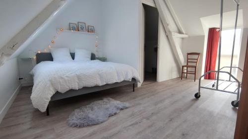a bedroom with a white bed and a wooden floor at Maisonnette au coeur de Grand-Fougeray in Grand-Fougeray