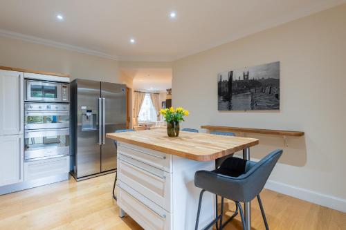 a kitchen with a island with a wooden counter top at 138 North Street - luxury 2 bed 2 bath with secret garden, summerhouse, putting green in St. Andrews