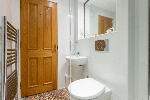 a bathroom with a toilet and a sink and a mirror at 138 North Street - luxury 2 bed 2 bath with secret garden, summerhouse, putting green in St. Andrews
