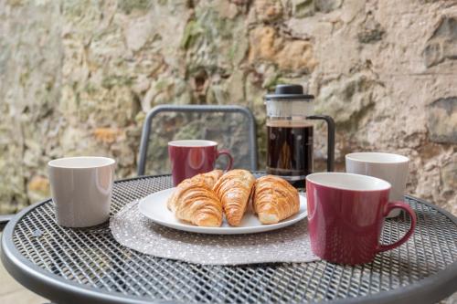 a table with a plate of croissants and coffee cups at 138 North Street - luxury 2 bed 2 bath with secret garden, summerhouse, putting green in St. Andrews