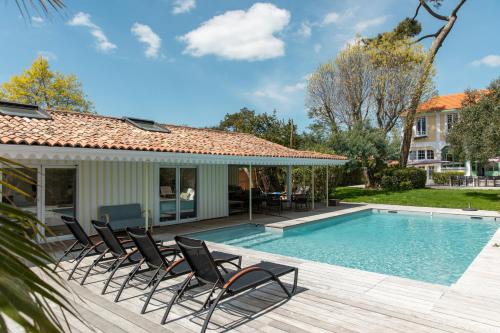 a pool with chairs next to a house at Villa Les Délices in Cap-Ferret