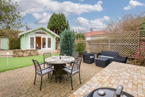 a patio with a table and chairs in a yard at 138 North Street - luxury 2 bed 2 bath with secret garden, summerhouse, putting green in St. Andrews