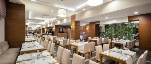 un restaurante con mesas blancas y sillas blancas en Ramada Resort By Wyndham Lara, en Lara