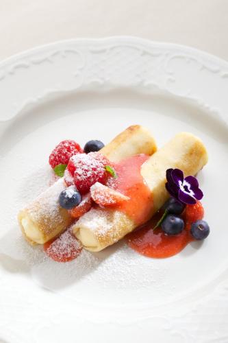 a plate of food with fruit and powdered sugar at Imperial Hotel & Restaurant in Vilnius
