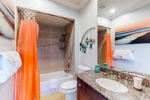 an orange shower curtain in a bathroom with a toilet and a sink at The Dawn Condominiums in Galveston