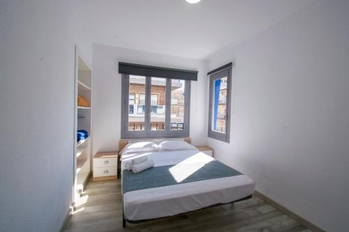 ein weißes Schlafzimmer mit einem Bett und zwei Fenstern in der Unterkunft COVESA III Centro Levante Beach in Benidorm