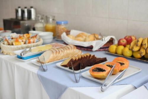 a table topped with plates of food and fruit at Hotel Brasil Pindamonhangaba in Pindamonhangaba