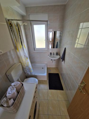 La salle de bains est pourvue d'un lavabo, de toilettes et d'une fenêtre. dans l'établissement Apartment Melody, à Metković