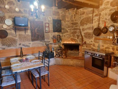 - une cuisine avec une table et un mur en pierre dans l'établissement CASA A ESCOLA, 
