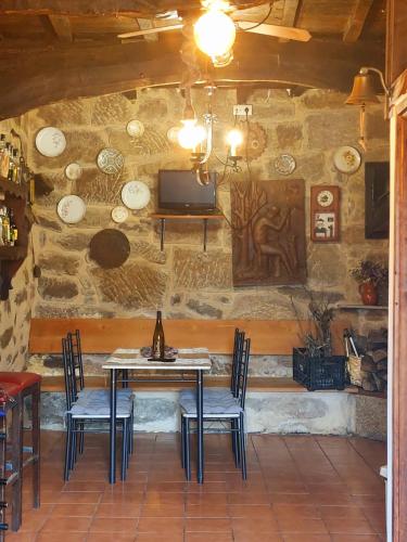 a table and chairs in a room with a stone wall at CASA A ESCOLA in Piñeiro