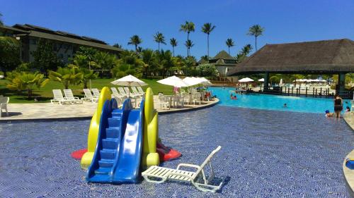 a resort with a pool with a slide and chairs at Flat Beach Class Resort Muro Alto in Porto De Galinhas