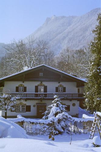 a house covered in snow with a mountain in the background at Pension Brucker in Aschau im Chiemgau