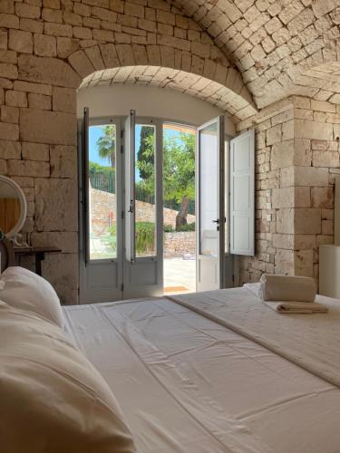 a bedroom with a large white bed in a stone wall at Donna Silvia Apartments in Castellana Grotte