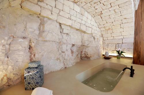 a bathroom with a bath tub in a stone wall at Donna Silvia Apartments in Castellana Grotte