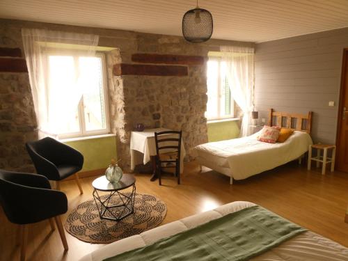 a bedroom with two beds and a table and chairs at Les Chambres d'Hôtes Le Triskèle in Rochepaule