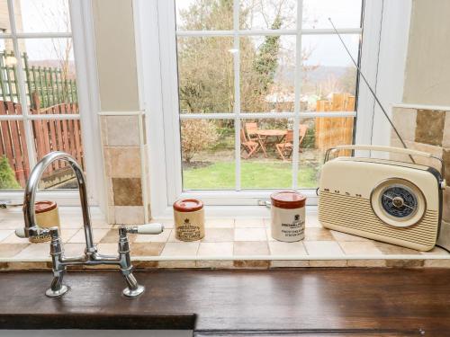 a kitchen counter with a toaster and two cups of coffee at Cherry Tree Cottage in Bingley