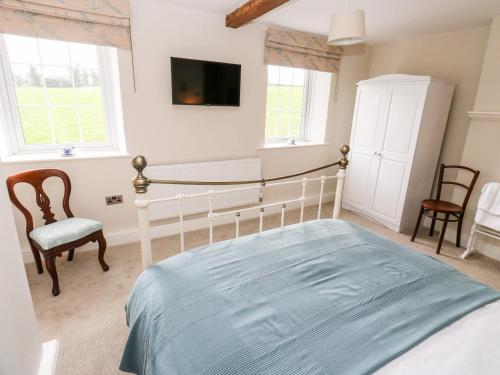 a bedroom with a bed and a tv on the wall at Cherry Tree Cottage in Bingley