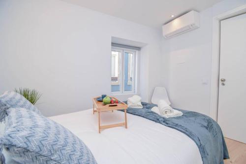 a white bedroom with a bed and a table at Charming Seaside Apartment - 1 min from the beach in Cascais
