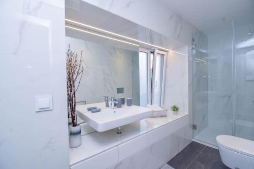 een witte badkamer met een wastafel en een spiegel bij Charming Seaside Apartment - 1 min from the beach in Cascais