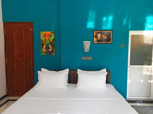 a bedroom with a blue wall and a bed with white pillows at Ayubowan Homestay Katunayake in Katunayaka