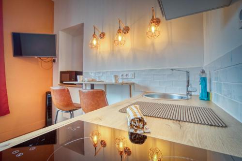 une cuisine avec un comptoir avec des chaises et des lumières dans l'établissement La Casa Roja - Championnet / Caserne de Bonne, à Grenoble