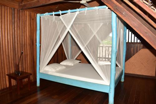 ein blaues und weißes Himmelbett in einem Zimmer in der Unterkunft LOCAVACATION Les Hauts Manguiers Villa 2 in Nosy Be