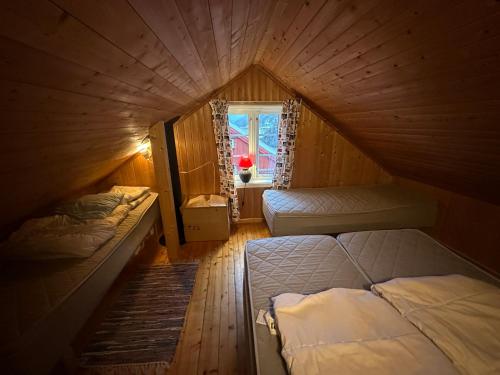 a attic room with two beds and a window at Handkleppveien 26 - Fishermans cabin in Straume