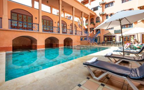 Hotel Oudaya & Spa في مراكش: مسبح مع كرسيين للصاله ومظله