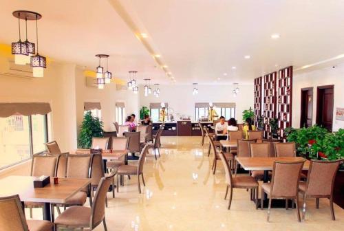 老街省的住宿－Cao Minh Hotel，餐厅设有桌椅,背景人员