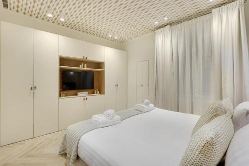 - une chambre blanche avec un lit et une télévision dans l'établissement Pick A Flat's Apartment in Saint Germain des Près - Rue du Cherche Midi, à Paris